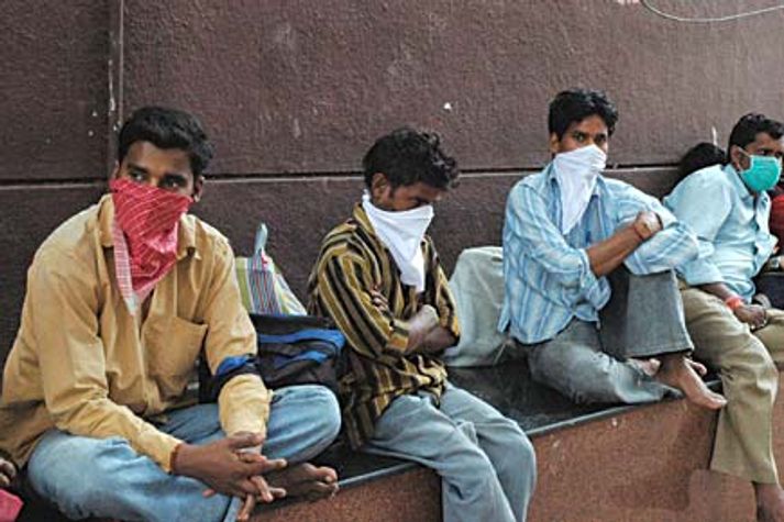 rail-passengers-cover-their-faces-outside-the-pune-railway-station