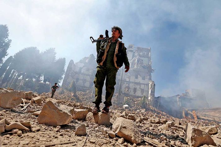 A Houthi fighter amidst the rubble of an air strike in Sana’a, Yemen