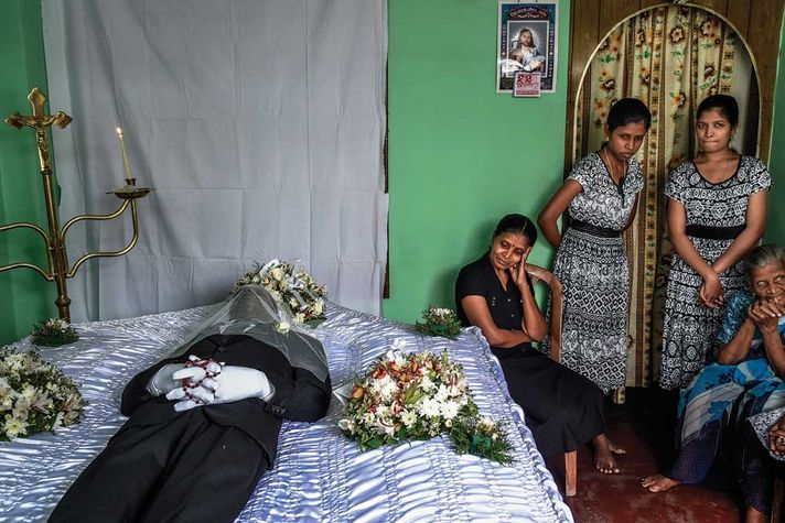 Delcia Fernando mourns with her daughters in front of the body of her husband at her house near St Anthony’s Church in Colombo