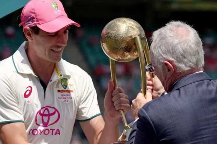 Pat Cummins collects the trophy from Allan Border