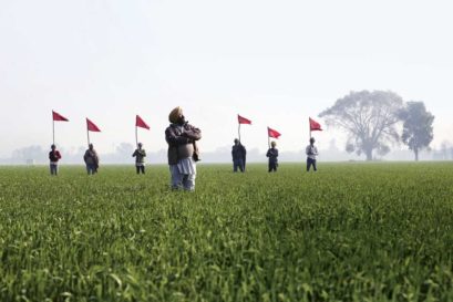 Dalit farmers hold flags of the Zamin Prapti Sangharsh Committee in the fields they have occupied in Balad Kalan