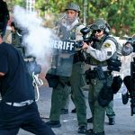 A law enforcement officer uses tear gas on a protester in Los Angeles, June 11, 2025